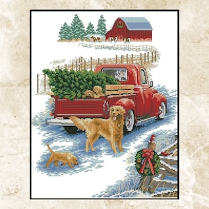 May include: Cross-stitch scene of a red pickup truck carrying a Christmas tree, with golden retrievers in the bed and foreground. A snowy landscape includes a red barn, evergreen trees, and a wooden fence. A festive wreath hangs on the fence.