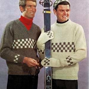 May include: Two people wearing vintage ski sweaters with checkered patterns. One sweater is gray with a red turtleneck, the other is cream-colored. They are holding a vintage ski and wearing matching mittens and a hat.