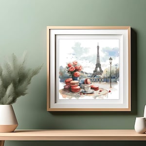 Op de afbeelding: Een aquarel schilderij van de Eiffeltoren in Parijs, Frankrijk. Het schilderij toont een tafel met roze macarons, een kopje koffie en een boeket rode rozen.