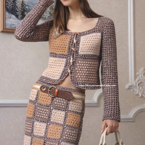 Peut inclure: Ensemble au crochet avec une jupe et une veste à motifs carrés dans des tons de marron, beige et crème. La veste a une encolure carrée et une fermeture boutonnée. Un foulard assorti et un sac à main marron et blanc complètent l'ensemble.