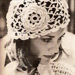 Puede incluir: Primer plano de un sombrero blanco de ganchillo con un diseño floral. El sombrero está hecho de un delicado patrón de tejido abierto. La imagen es en blanco y negro.