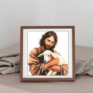 May include: A framed painting of a man with a beard holding a white lamb in his arms. The man is wearing a brown robe and the background is white.