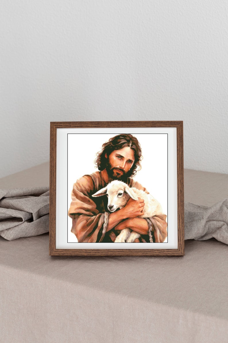 May include: A framed painting of a man with a beard holding a white lamb in his arms. The man is wearing a brown robe and the background is white.