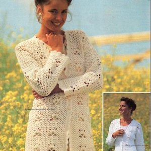 May include: A cream-coloured, long crochet cardigan with floral-shaped cutouts and scalloped edges. The cardigan is buttoned down the front and worn over a floral print dress. The image includes a smaller inset image of the same cardigan.