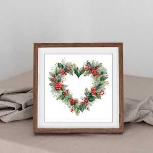 Può includere: Stampa incorniciata con una ghirlanda a forma di cuore, composta da fogliame verde e bacche rosse. La cornice in legno è posta su una superficie neutra. Evoca un tema festivo o stagionale, come Natale o San Valentino.