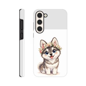 May include: A white and gray phone case featuring a cartoon husky puppy wearing a floral crown. The puppy has blue eyes and a pink tongue. The case has a white and gray design.