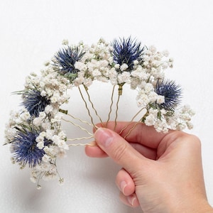 Puede incluir: Un juego de seis horquillas doradas adornadas con flores secas de aliento de bebé blancas y cardos azules.