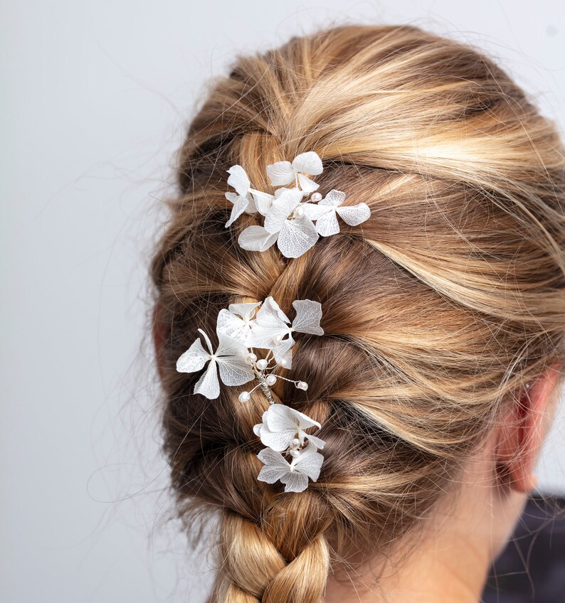 May include: A blonde woman with a French braid in her hair. The braid is decorated with white flower hair clips.
