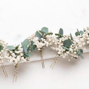 May include: Five gold hair pins with white baby's breath and eucalyptus sprigs attached.