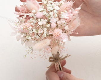 May include: A small bouquet of dried flowers in shades of pink and white. The bouquet is tied with twine and includes baby's breath, bunny tails, and other dried flowers.
