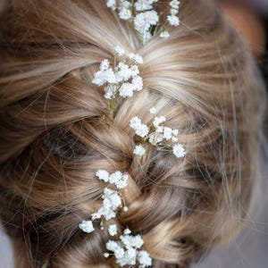May include: A braided hairstyle with small white flowers woven throughout.