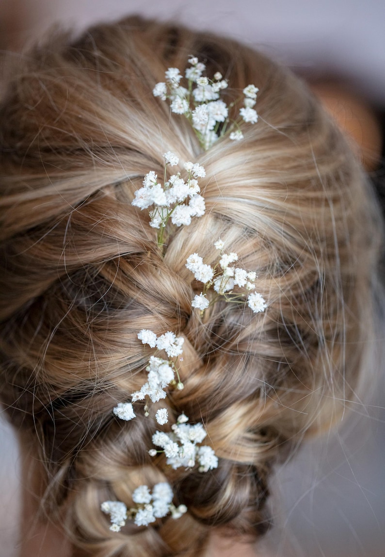 May include: A braided hairstyle with small white flowers woven throughout.