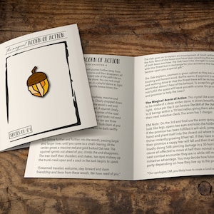 Op de afbeelding: Een gevouwen kaart met de tekst "The Magical Acorn of Action" en een serienummer. De kaart toont een kleurrijke eikelspeldillustratie. De achtergrond is een houten oppervlak.