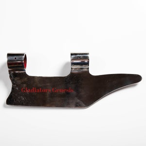 May include: A silver metal gladiator helmet with two metal loops on the top and the text "Gladiators Genesis" engraved on the front.