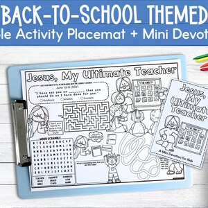May include: A blue clipboard holds a black and white Bible activity placemat and a mini devotion booklet. The placemat features the text "Jesus, My Ultimate Teacher" and includes a word scramble and a maze. Colour pencils are visible.