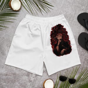 May include: White athletic shorts featuring a graphic print of a male anime character with spiky pink hair, wearing a dark high-collared jacket, surrounded by a dark red and black swirling aura on the right leg of the garment.