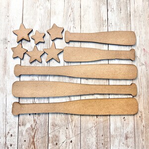 May include: Wooden craft project featuring a baseball bat design in the shape of an American flag. The flag is made up of five bats and a field of stars.