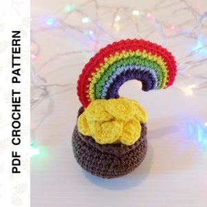 Könnte beinhalten: Ein gehäkelter Topf voller Gold mit einem Regenbogen darauf. Der Topf ist braun und die Goldmünzen sind gelb. Der Regenbogen ist rot, orange, gelb, grün, blau, indigo und violett.