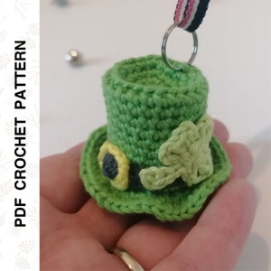 May include: A green crocheted leprechaun hat with a shamrock and a black and yellow buckle. The hat is attached to a silver key ring.