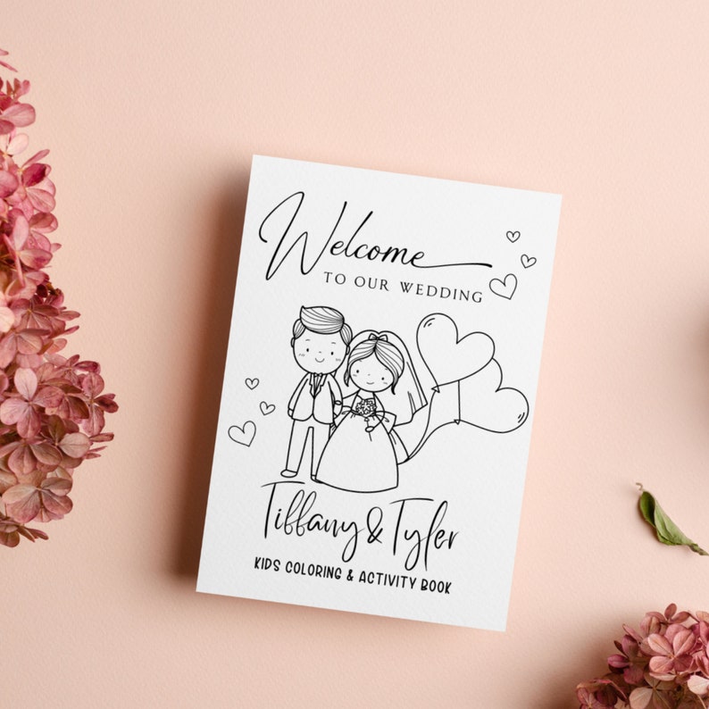 May include: A black and white coloring book with a cartoon bride and groom holding hands. The book says "Welcome to our wedding" and "Tiffany & Tyler Kids Coloring & Activity Book".