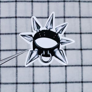 May include: A black leather choker with silver spikes. The choker has a silver ring in the centre.