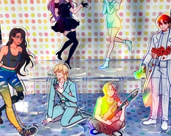 May include: Acrylic standees featuring anime-style characters in various poses. The characters are depicted with vibrant colors and detailed designs. The standees are on clear bases, with a colorful polka dot background.