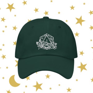 Peut inclure: Une casquette de baseball vert foncé avec un motif brodé blanc d'un dé à vingt faces avec le numéro un affiché. Le dé est entouré d'une couronne de feuilles et d'une bannière qui dit "Roll With It".
