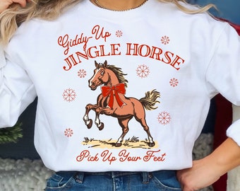 Puede incluir: Sudadera blanca con una ilustración de un caballo rojo y marrón y el texto "Giddy-Up Jingle Horse Pick Up Your Feet".