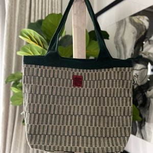 May include: A green and white striped tote bag with a small red label that says "Design Goods".