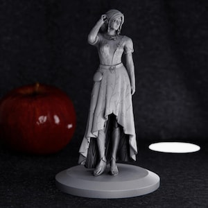 Peut inclure: Une figurine blanche d'une femme portant une longue robe avec une fente haute. La figurine est debout sur une base ronde.