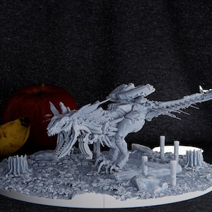 Könnte beinhalten: Ein weißes, detailliertes, 3D-gedrucktes Modell einer skelettartigen, drachenartigen Kreatur mit Flügeln und einem langen Schwanz. Das Modell ist auf einer runden Basis mit einer strukturierten Oberfläche platziert, die einem felsigen Gelände ähnelt.