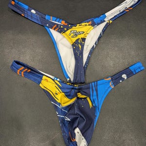 May include: Two pairs of blue, yellow, and white patterned underwear with a white lining. The underwear has a string tie at the back and the brand name "Ryze" is printed on the front.