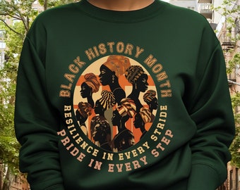 May include: Green sweatshirt with a circular graphic design featuring a group of Black women with colorful headwraps. The graphic text reads "Black History Month" and "Resilience in Every Step, Pride in Every Stride."