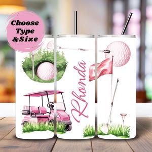 May include: A white cylindrical tumbler with a straw featuring pink golf-themed illustrations including a golf cart, a golf ball in a hole, a flag, and a golf club. The name Rhonda is printed in pink script. A pink circle contains the text Choose Type & Size.