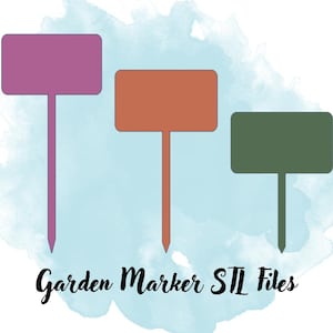 May include: Three garden markers in shades of purple, orange, and green. Each marker has a rectangular label and a pointed stake. The text "Garden Marker STL Files" is written in black script below the markers.