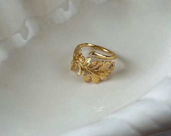 May include: A gold-toned ring with a leaf design. The ring is open and adjustable.