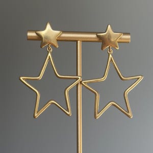 May include: Gold star-shaped earrings with a smaller star charm at the top of each earring.