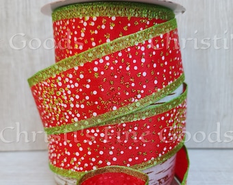 May include: A spool of red ribbon featuring a pattern of white dots and gold glitter accents. The ribbon has a metallic green stitched edge and is wrapped around a cylindrical core with a light brown wood grain texture.