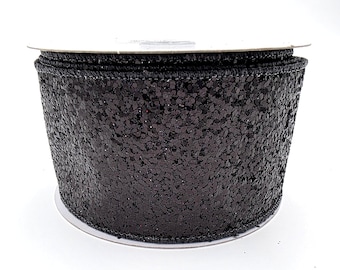 Peut inclure: Un rouleau de ruban noir à paillettes. Le ruban large est densément recouvert de paillettes, ce qui lui donne un aspect texturé. Il est enroulé autour d'un noyau en carton, adapté aux travaux manuels ou décoratifs.