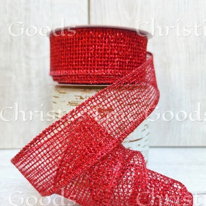 Könnte beinhalten: Rotes Glitzer-Meshband mit quadratischem Muster. Das Band ist auf einer Spule aufgerollt und auf einer weißen Holzoberfläche abgelegt.