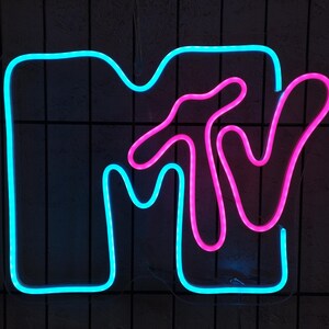 May include: A neon sign with the MTV logo. The logo is made of blue and pink neon tubing. The sign is mounted on a black wall.