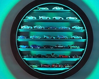 May include: A round, dark brown display case with multiple shelves, illuminated by a soft blue light. The case is filled with a collection of miniature toy cars in various colors and designs, showcasing a hobbyist's collection.