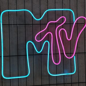 May include: A neon sign with the MTV logo. The "M" is blue and the "TV" is pink.