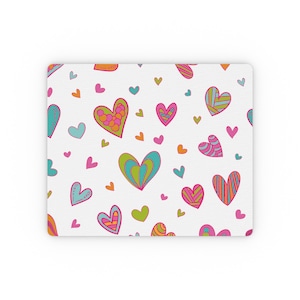 May include: A white mouse mat with a repeating pattern of colourful hearts. The hearts are in shades of pink, blue, green, and orange. Some of the hearts have a swirl pattern.