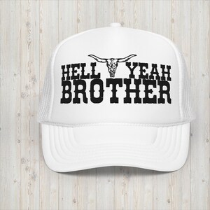 Könnte beinhalten: Weiße Trucker-Kappe mit einem schwarzen gestickten Design, das "Hell Yeah Brother" mit einem Totenkopf und Hörnern über dem Text sagt.