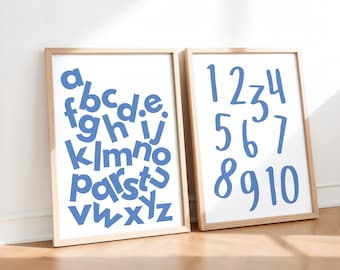 May include: Two framed prints with a white background. One features the alphabet in blue, the other displays numbers 1-10 in blue. The frames are a light wood color, and the prints are leaning against a white wall.