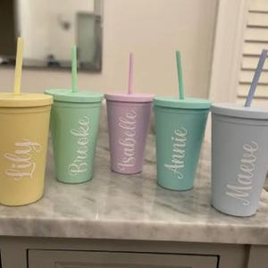 May include: Five personalized pastel-colored tumblers with matching straws. The tumblers are labeled "Lily", "Brooke", "Isabelle", "Annie", and "Maeve".
