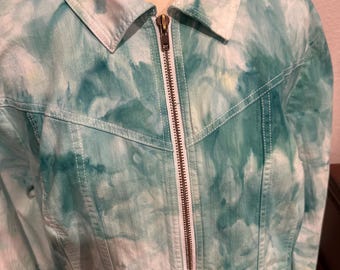 Könnte beinhalten: Türkis-weiße Batikjacke mit durchgehendem Reißverschluss und Kragen. Die Jacke hat weiße Nähte und ein klassisches Jeansjacken-Design.
