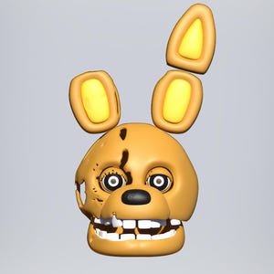 May include: A yellow animatronic head with a cracked face and large, yellow ears. The head has a wide, toothy grin and black eyes with white pupils.