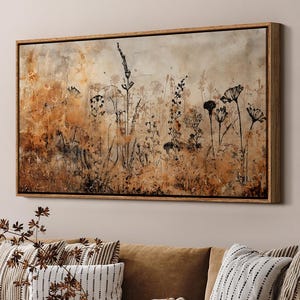 May include: A brown leather sectional sofa with a variety of throw pillows in a living room setting. The sofa is in front of a large framed print of a watercolor painting of a field of wildflowers.